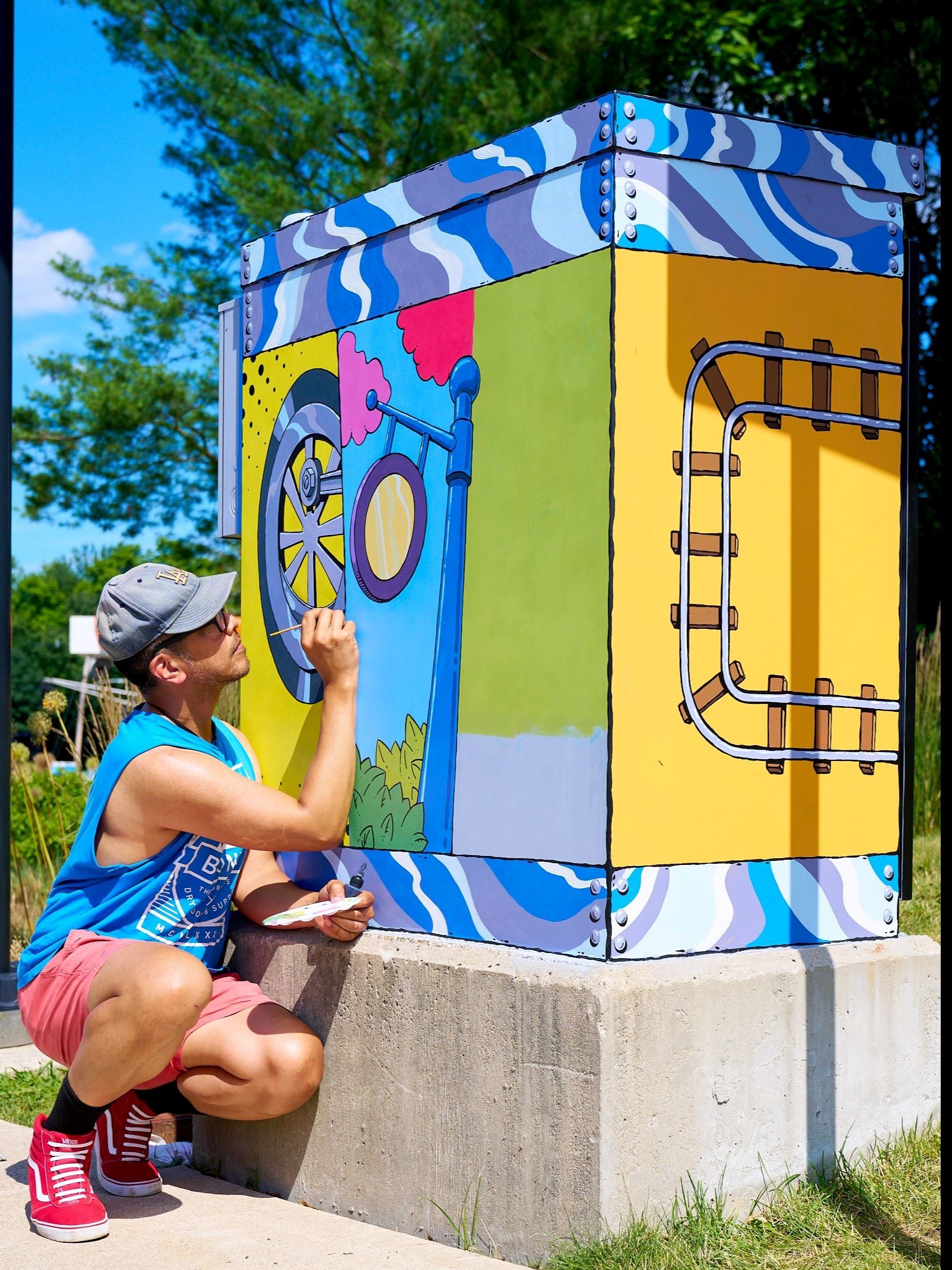 A man painting a colorful electrical box