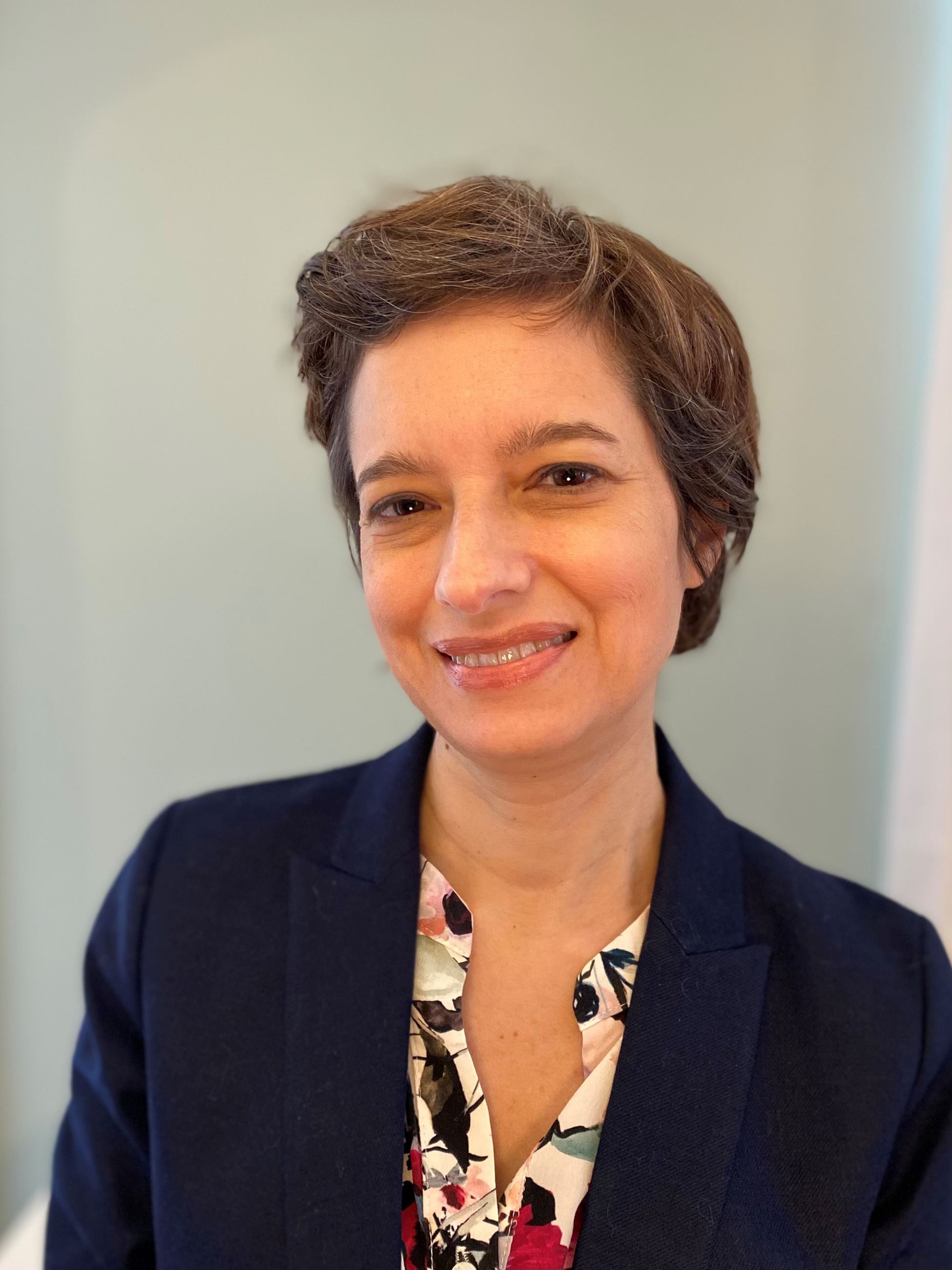 Woman smiling in a navy blue jacket with a print blouse