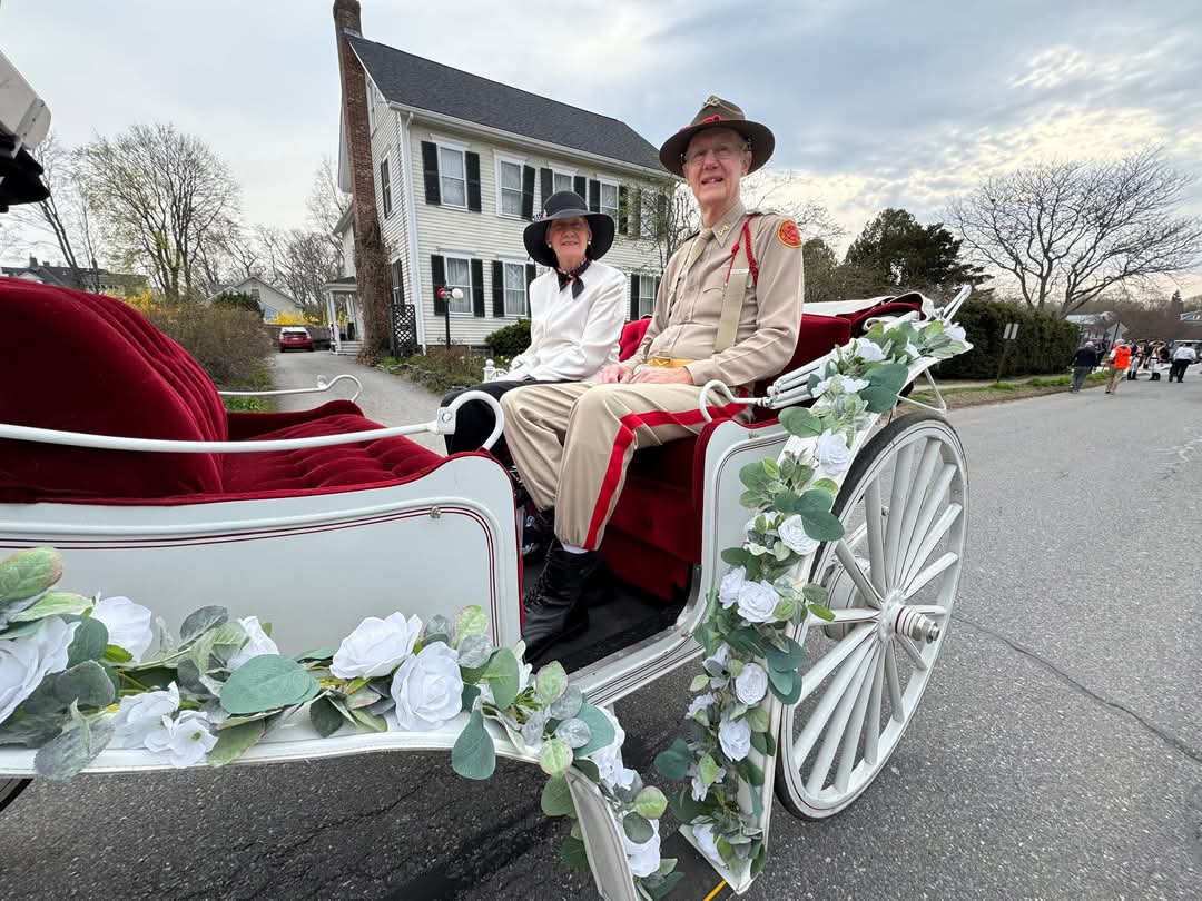 Honored citizen Sandy Smith rides in the parade in a white horse drawn carriage